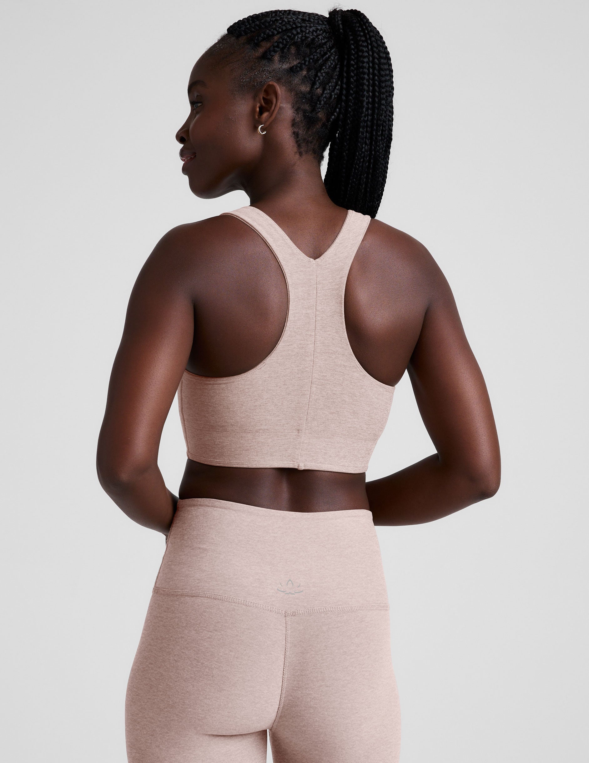 model wearing a pink scoop neck racerback long line sports bra and leggings set on a light gray background.