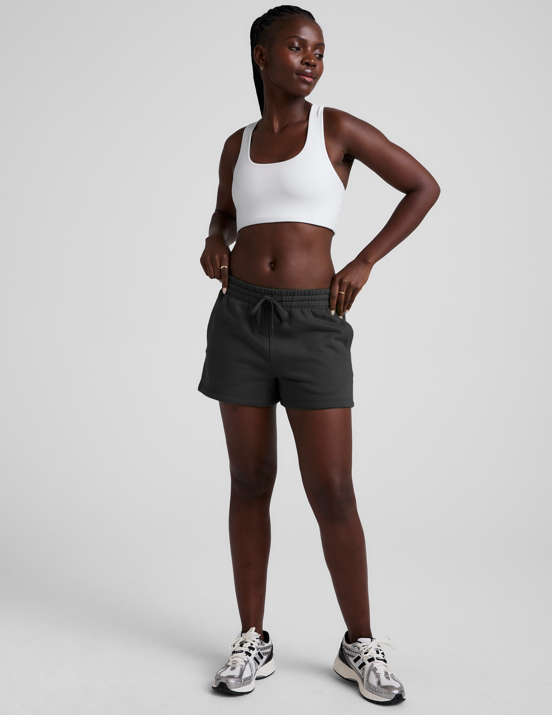 woman wearing a white sports bra and black shorts on a plain background.