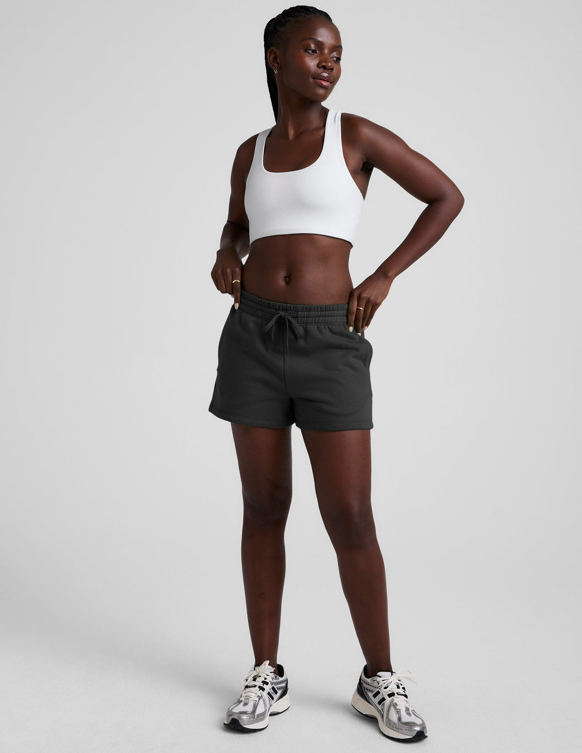 woman wearing a white sports bra and black shorts on a plain background.