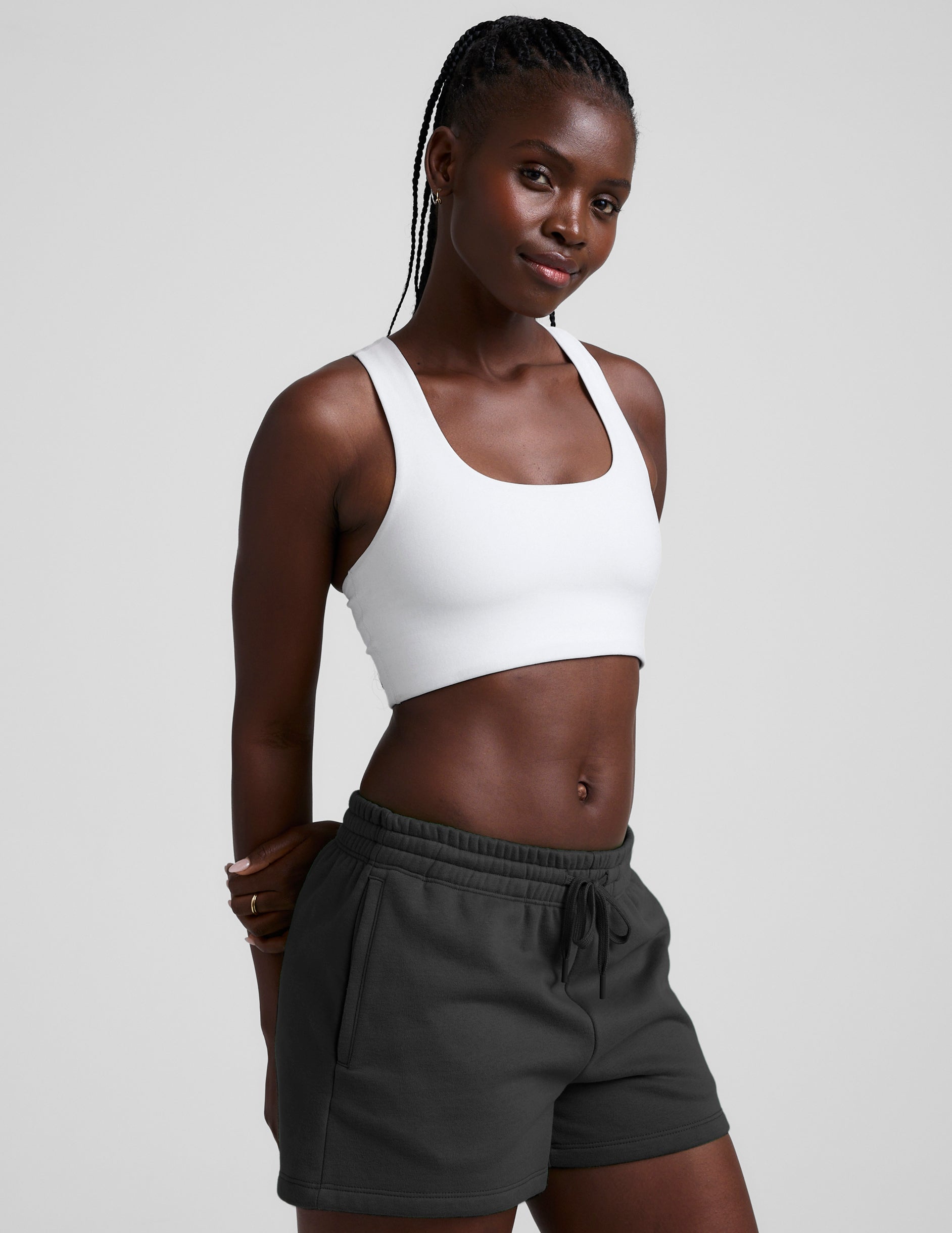 woman wearing a white sports bra and black shorts on a plain background.
