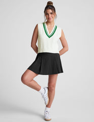 white relaxed fit cable knit vest with a neckline with contrast color stripe​, rib hemband, neckline and armhole​s. 