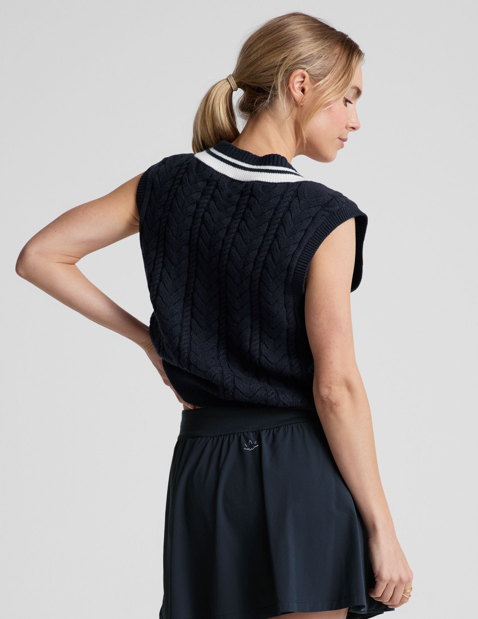 blue relaxed fit cable knit sweater vest with a v neckline with contrast color stripe.