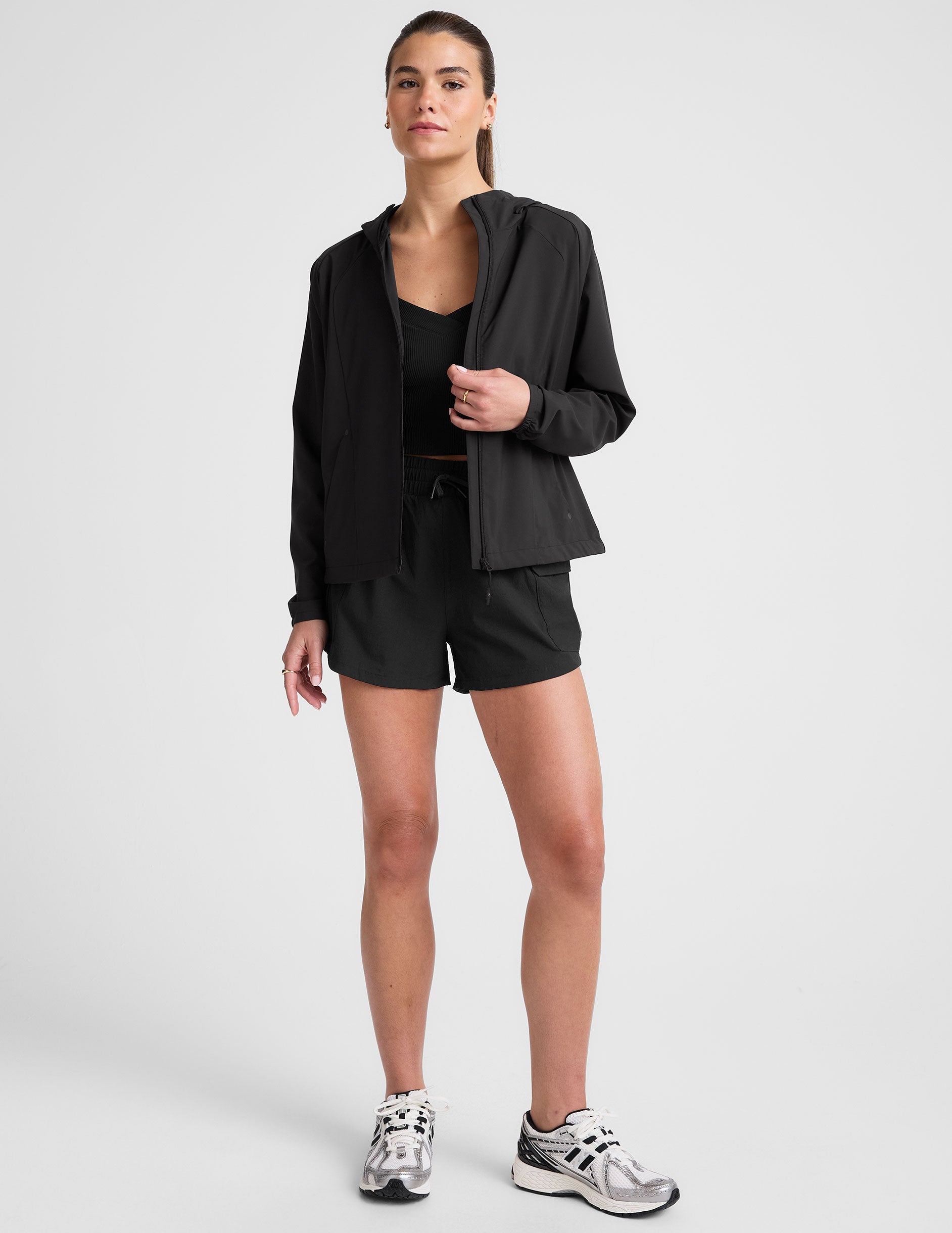 model wearing a black jacket and shorts on a light gray background.