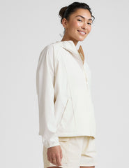 model wearing a white zip-up jacket with hood and shorts on a plain background.