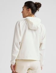model wearing a white zip-up jacket with hood and shorts on a plain background.