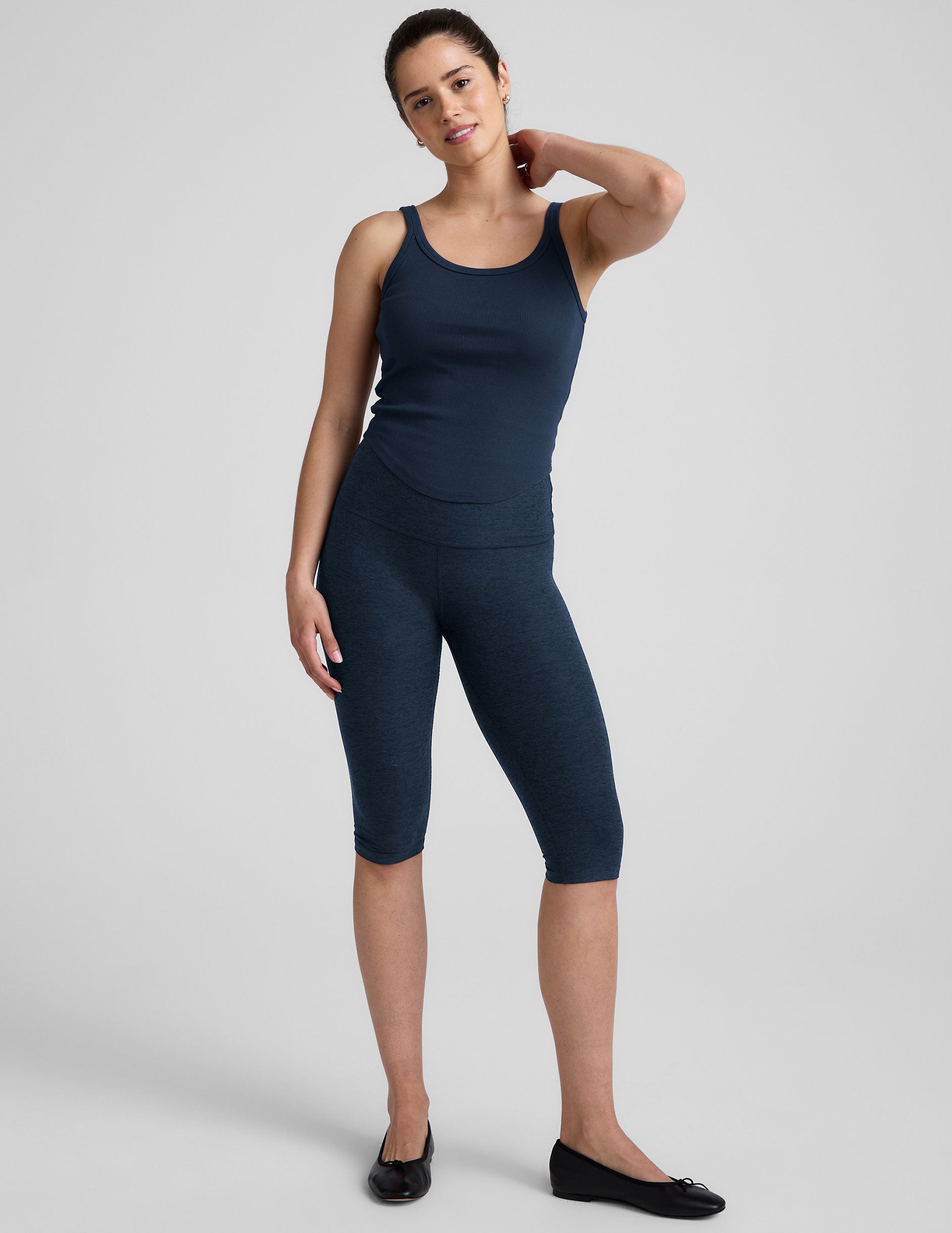 model is wearing a navy blue scoop neck ribbed tank top against a plain background.