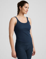 model is wearing a navy blue scoop neck ribbed tank top against a plain background.