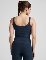 model is wearing a navy blue scoop neck ribbed tank top against a plain background.