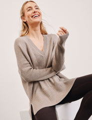 Woman wearing a beige v-neck sweater against a plain background.
