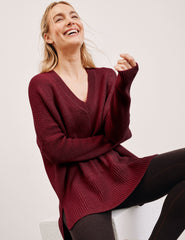 woman wearing a red v-neck sweater sweater against a plain background.