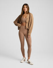 woman wearing a brown button up ribbed cardigan against a plain background.