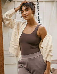 woman wearing a cream cardigan  on a porch.