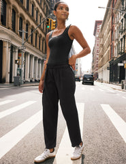 model in black bodysuit and black cargo style pants standing on a city street.