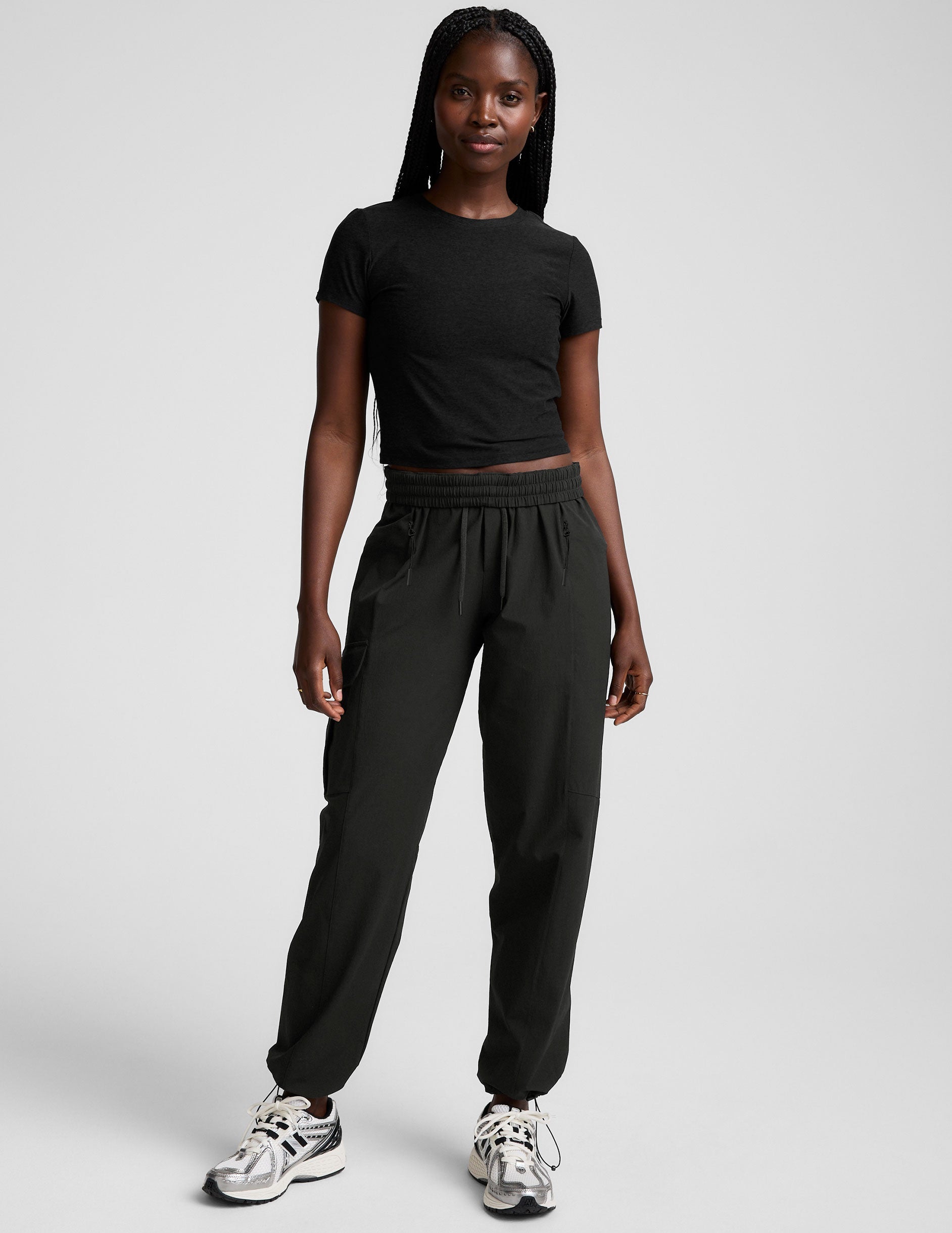 model wearing a black t-shirt and black cargo style pants on a white background.