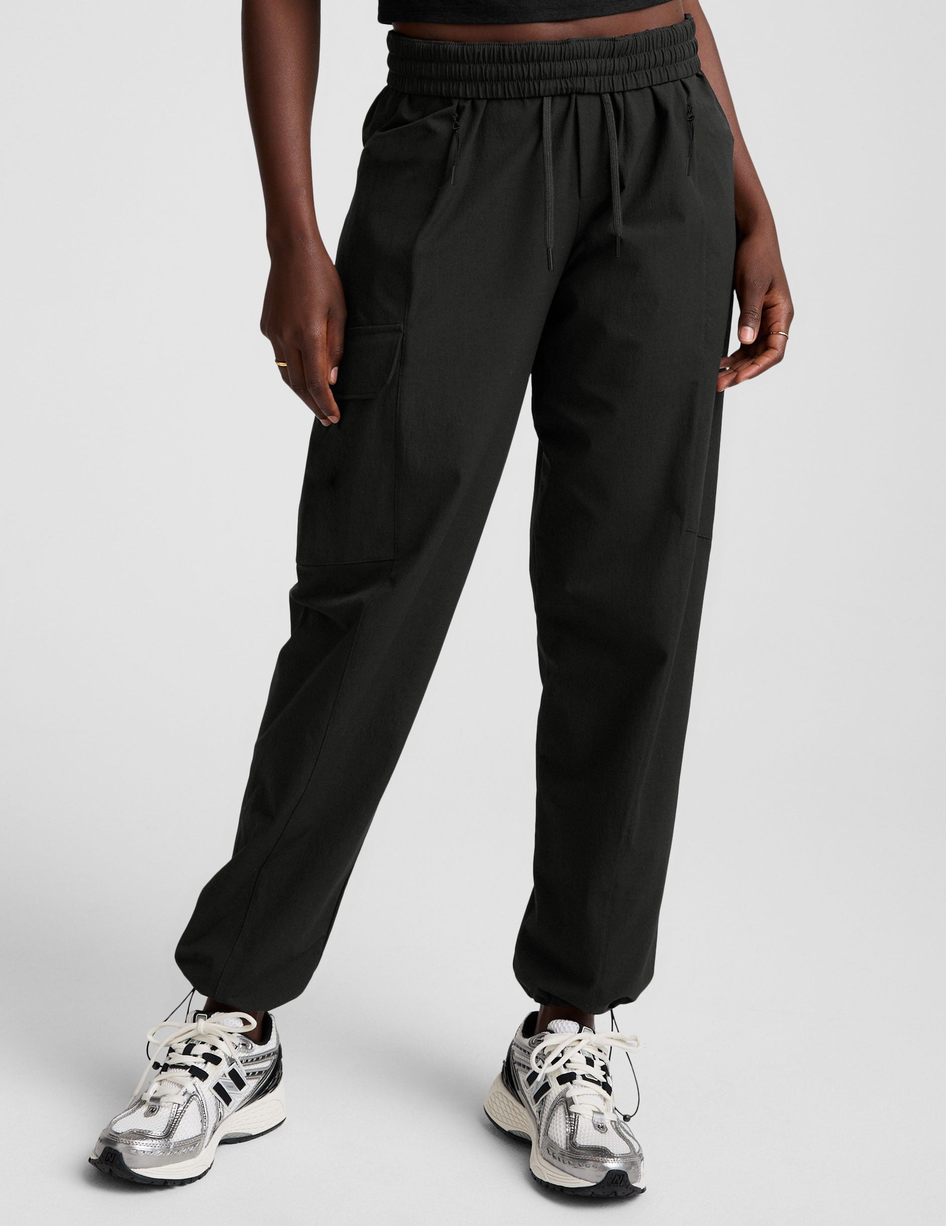 model wearing a black t-shirt and black cargo style pants on a white background.