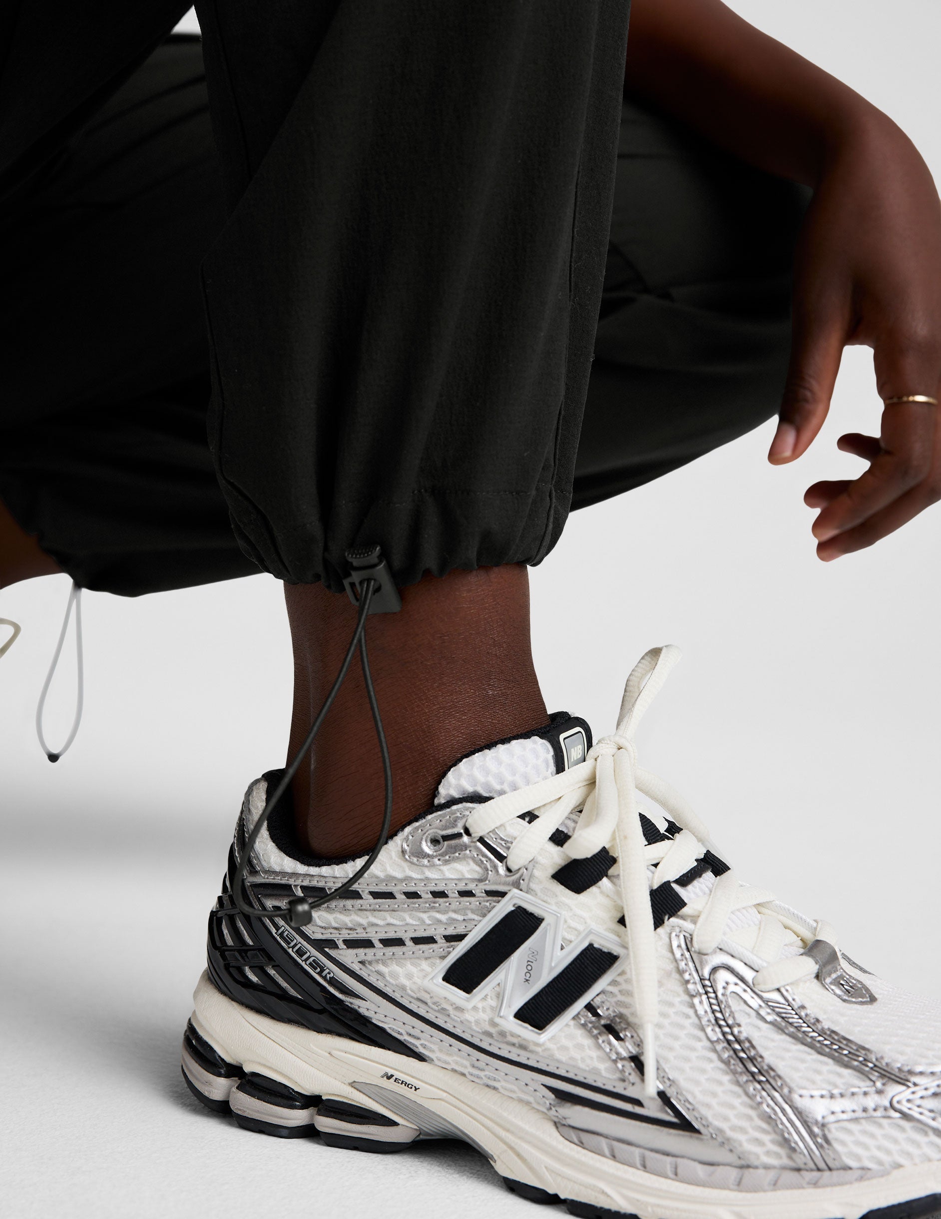 model wearing a black t-shirt and black cargo style pants on a white background.