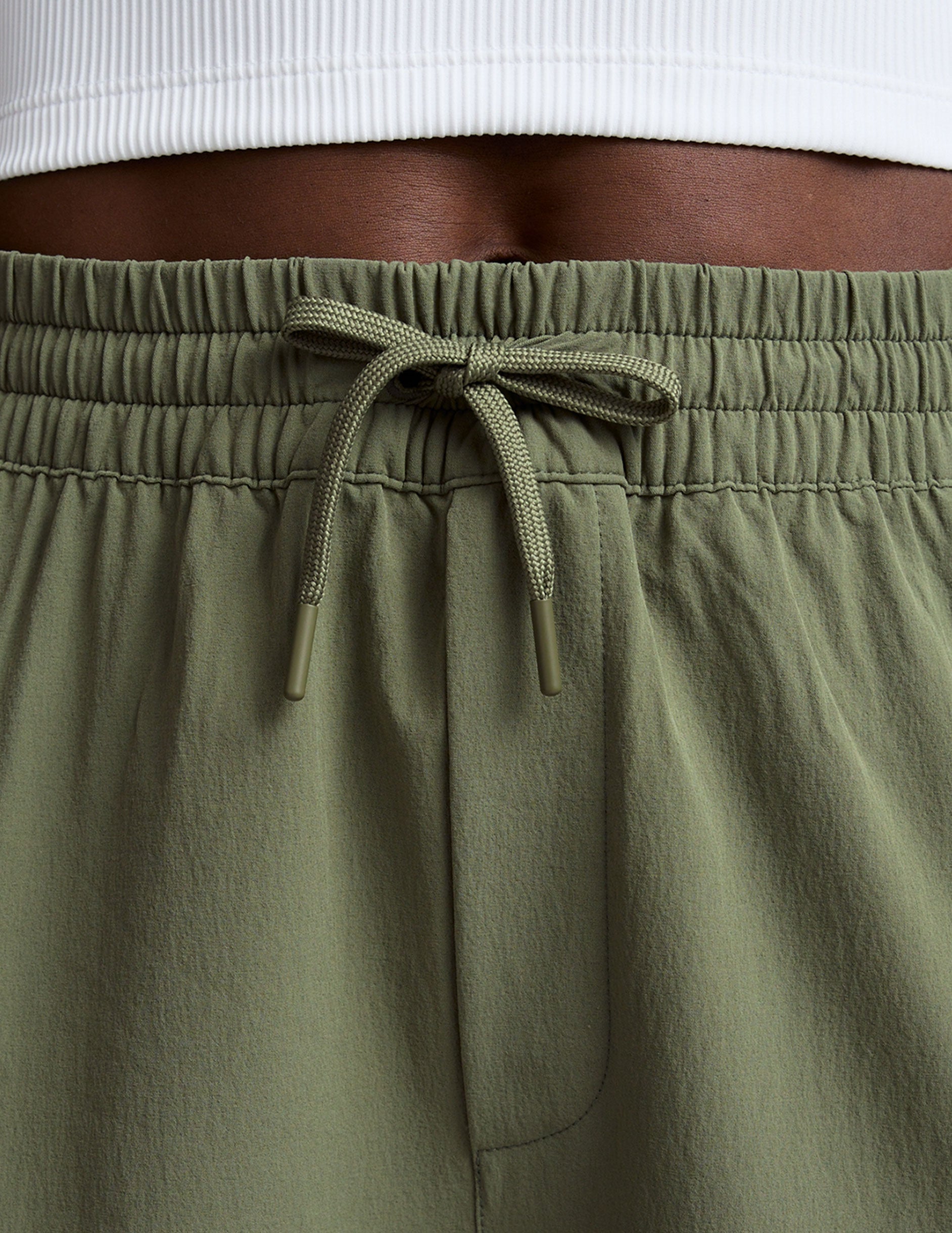 close-up of olive green cargo pants with a drawstring on a plain background.