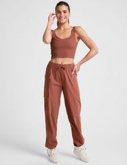 model wearing an orange ribbed tank top and orange cargo pants on a white background.