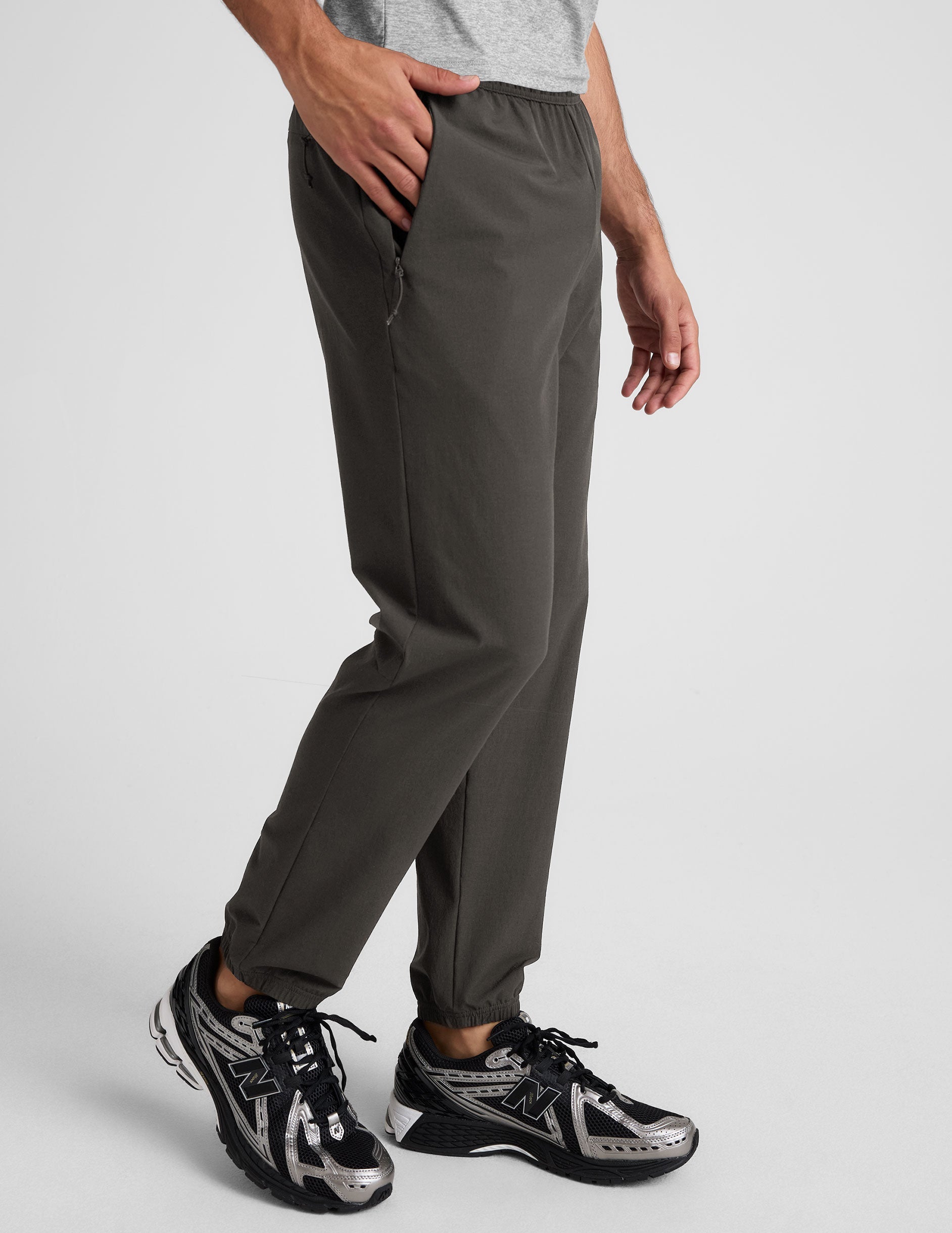 dark gray joggers and a grey t-shirt on a plain background.