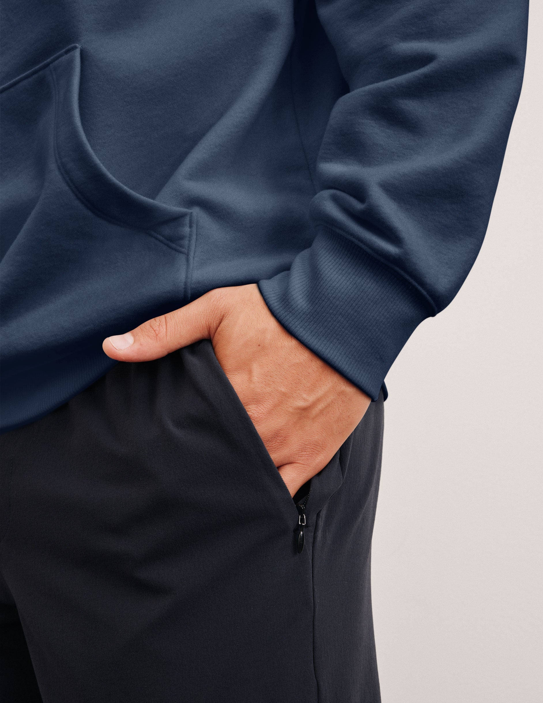 man wearing a blue hoodie and blue joggers on a plain background.