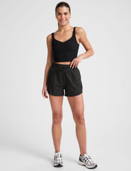 model wearing a black tank top and black shorts on a white background.