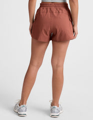 model wearing a gray tank top and auburn shorts on a plain background.