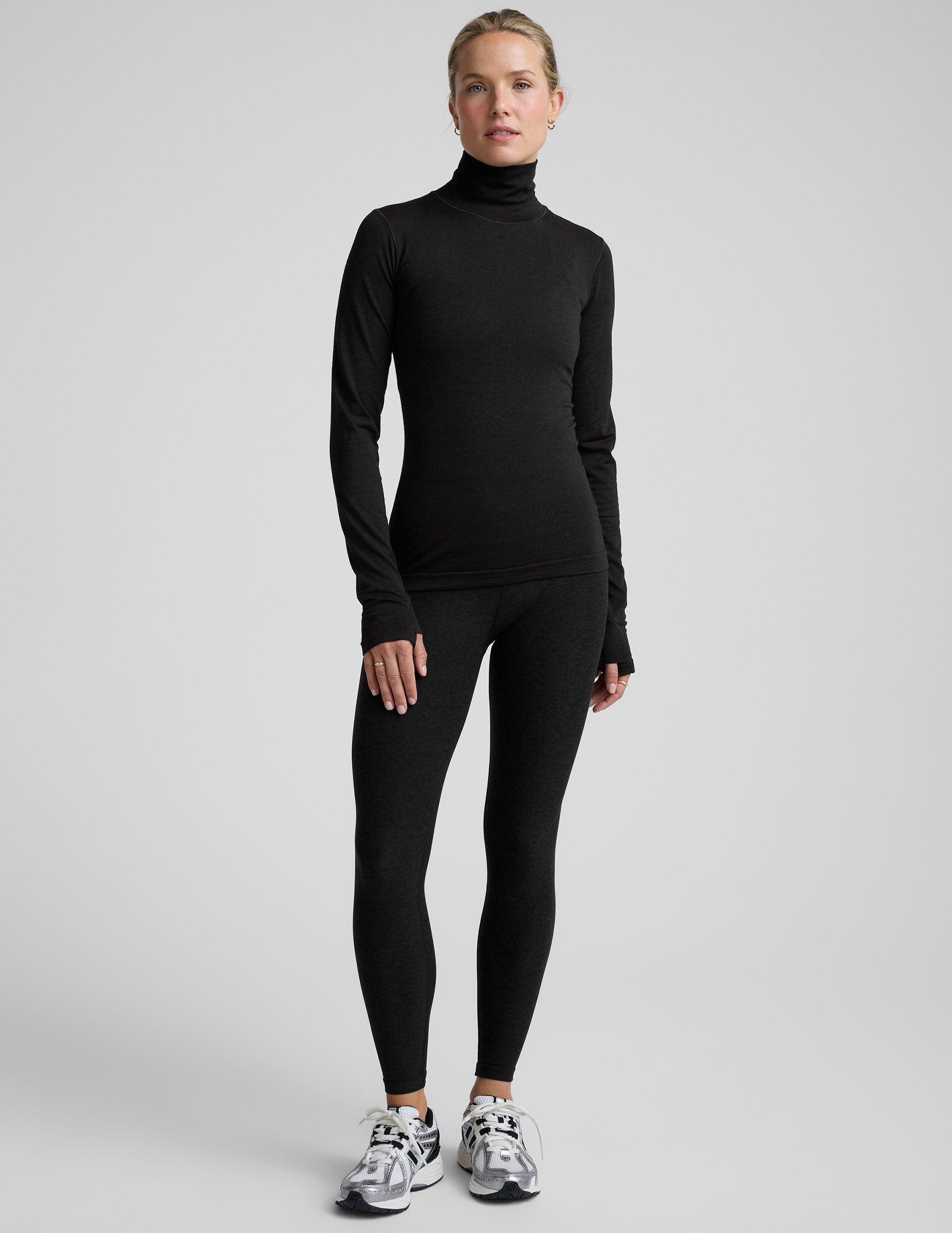 model wearing a black turtleneck shirt against a plain background.