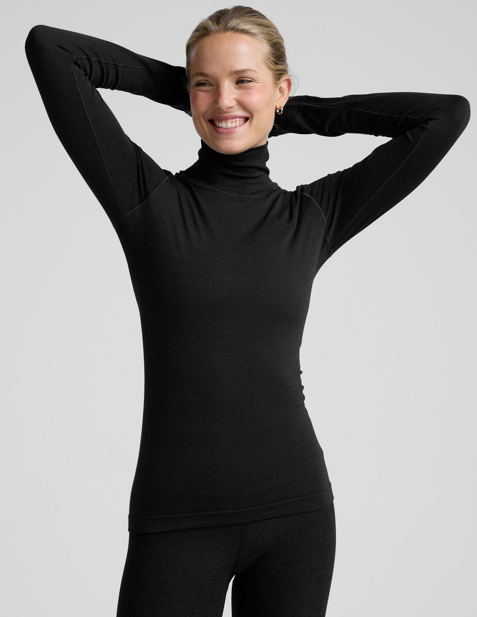 model wearing a black turtleneck shirt against a plain background.