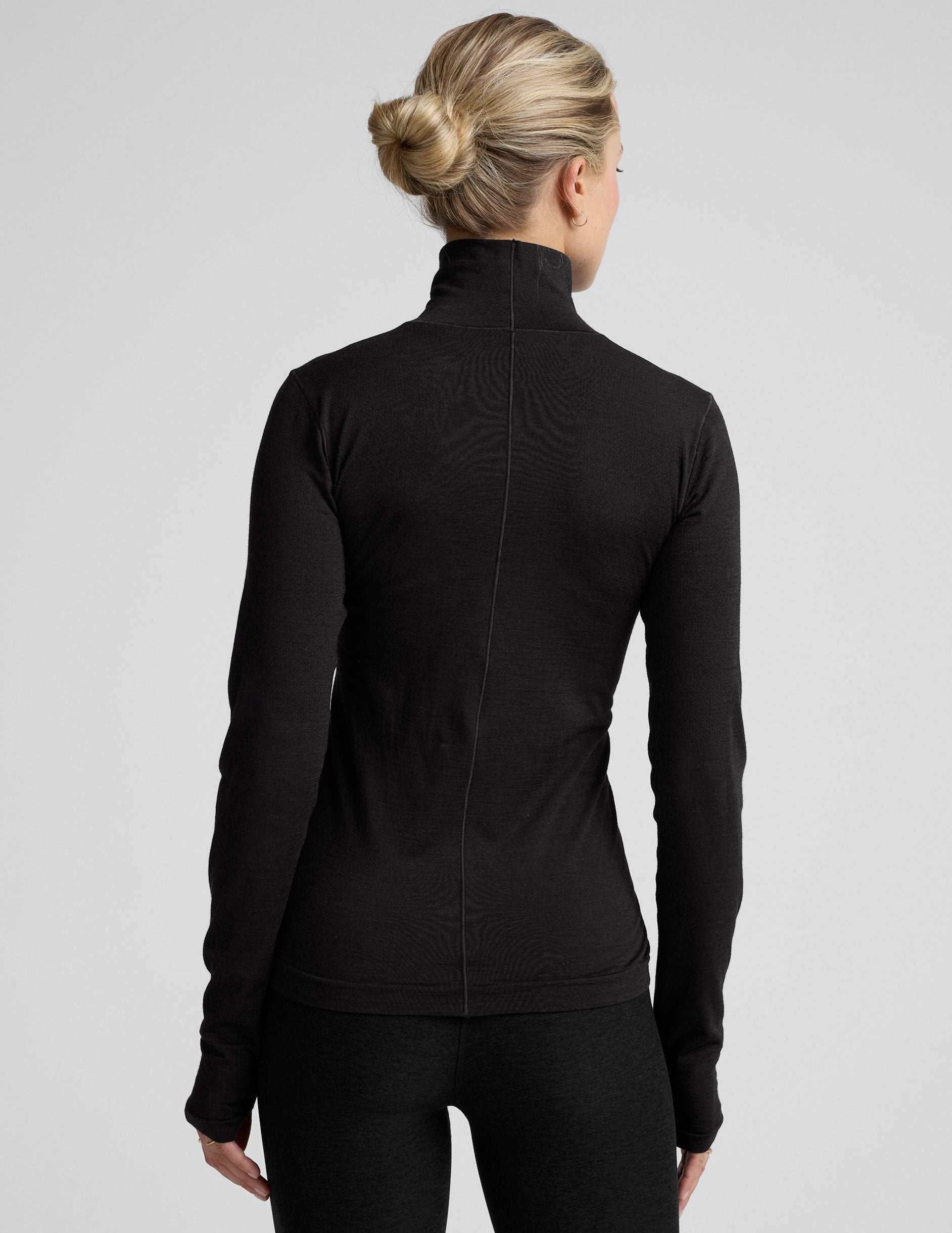 model wearing a black turtleneck shirt against a plain background.