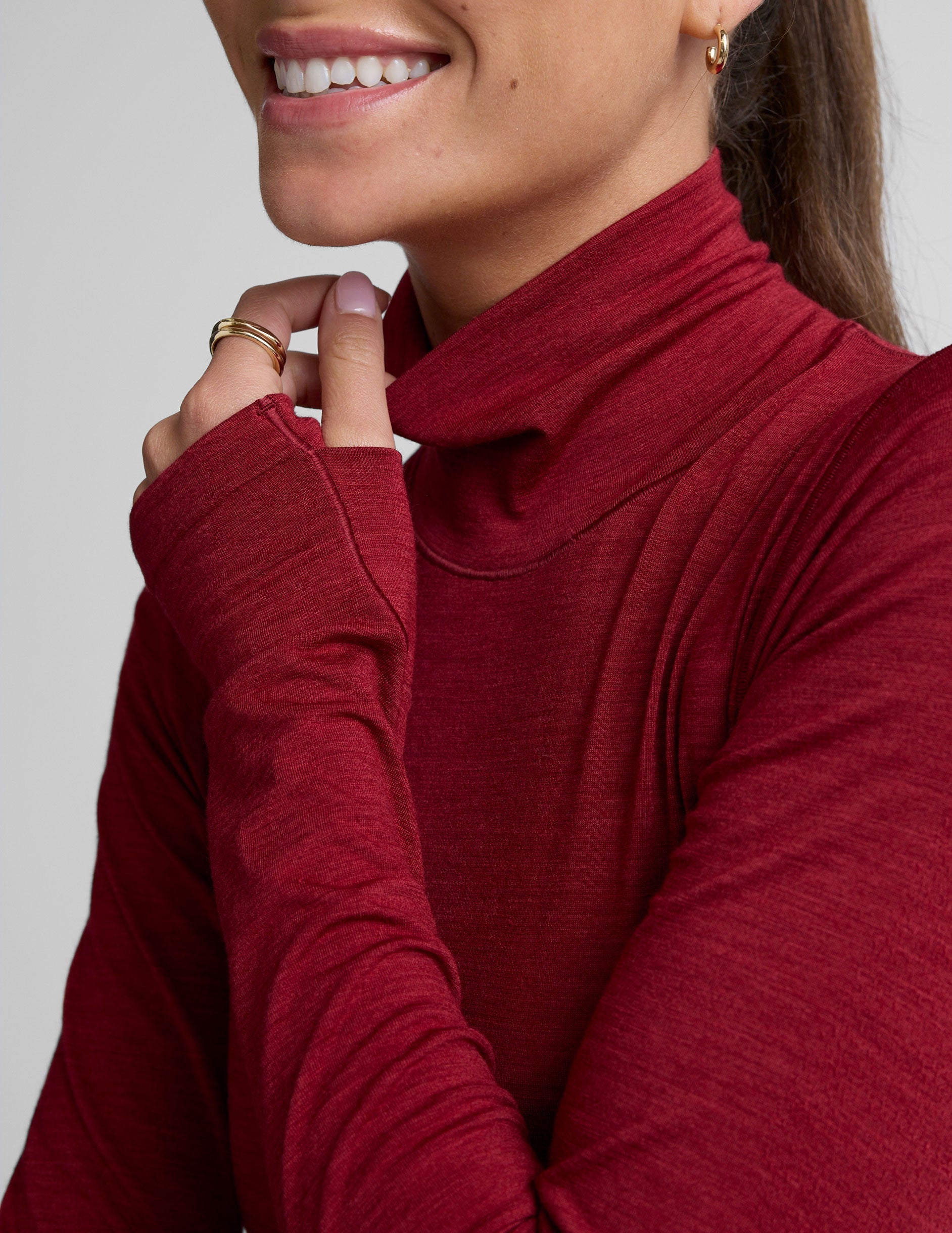 model wearing a red turtleneck long sleeve top and black pants on a plain background.