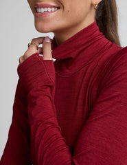 model wearing a red turtleneck long sleeve top and black pants on a plain background.