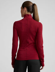 model wearing a red turtleneck long sleeve top and black pants on a plain background.