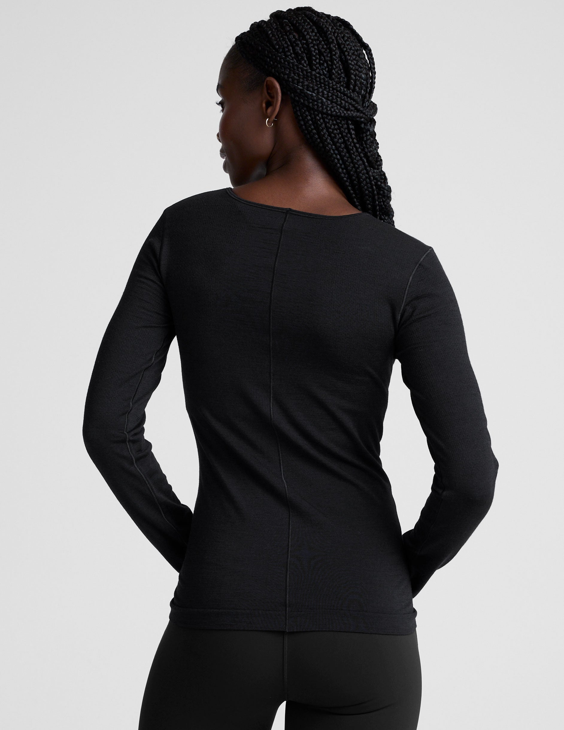 model wearing a black long sleeve crewneck top against a plain background.