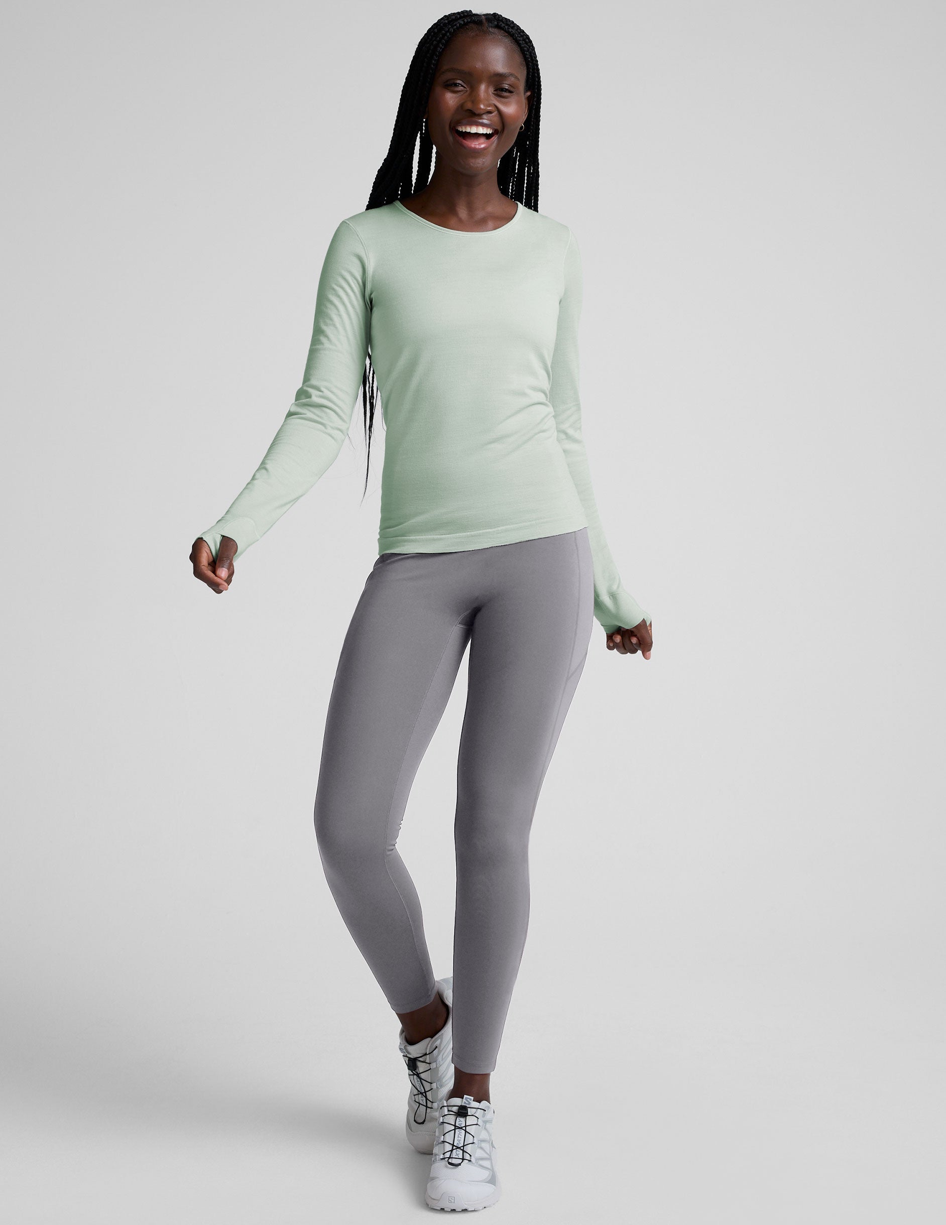 model wearing a light green long-sleeve crewneck top and gray leggings on a plain background.
