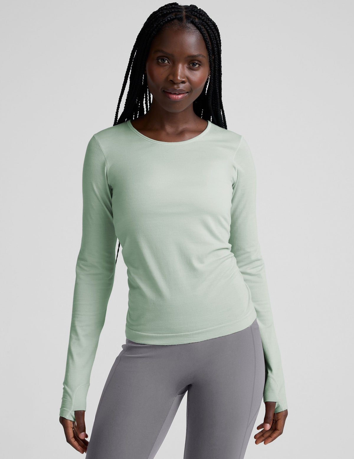model wearing a light green long-sleeve crewneck top and gray leggings on a plain background.