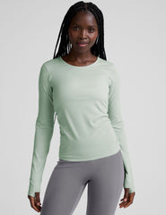 model wearing a light green long-sleeve crewneck top and gray leggings on a plain background.
