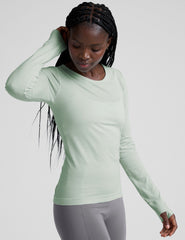 model wearing a light green long-sleeve crewneck top and gray leggings on a plain background.