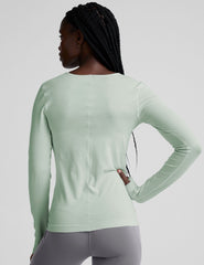 model wearing a light green long-sleeve crewneck top and gray leggings on a plain background.