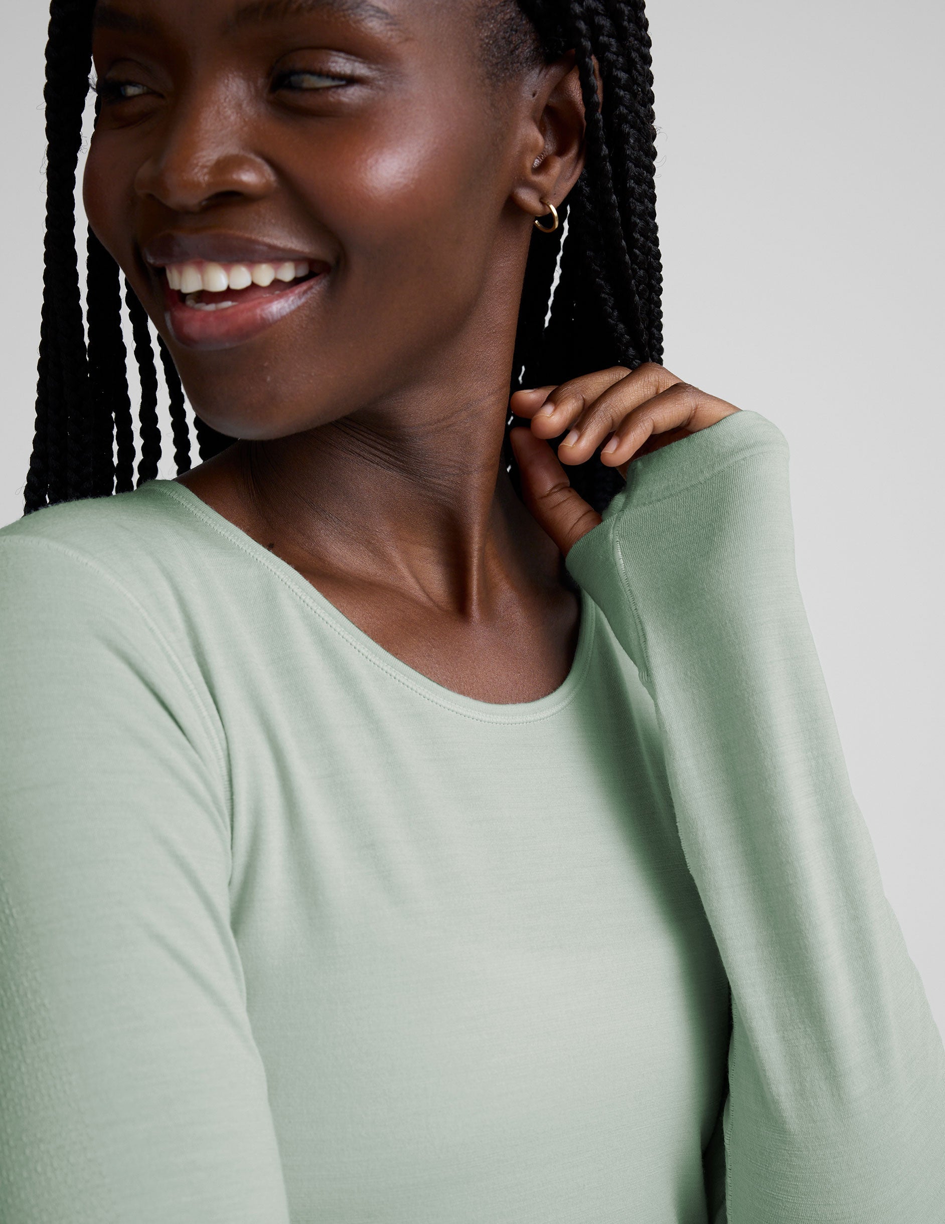 model wearing a light green long-sleeve crewneck top and gray leggings on a plain background.