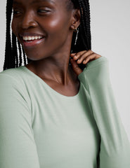 model wearing a light green long-sleeve crewneck top and gray leggings on a plain background.