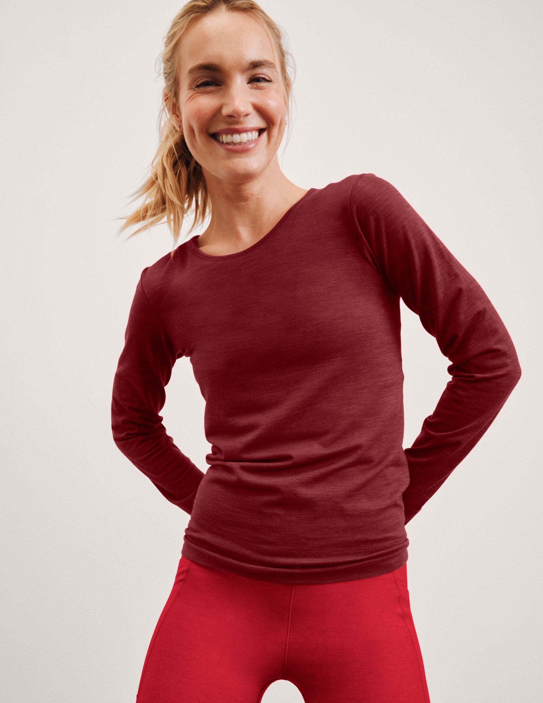 woman wearing a red long-sleeve top and red leggings on a plain background.