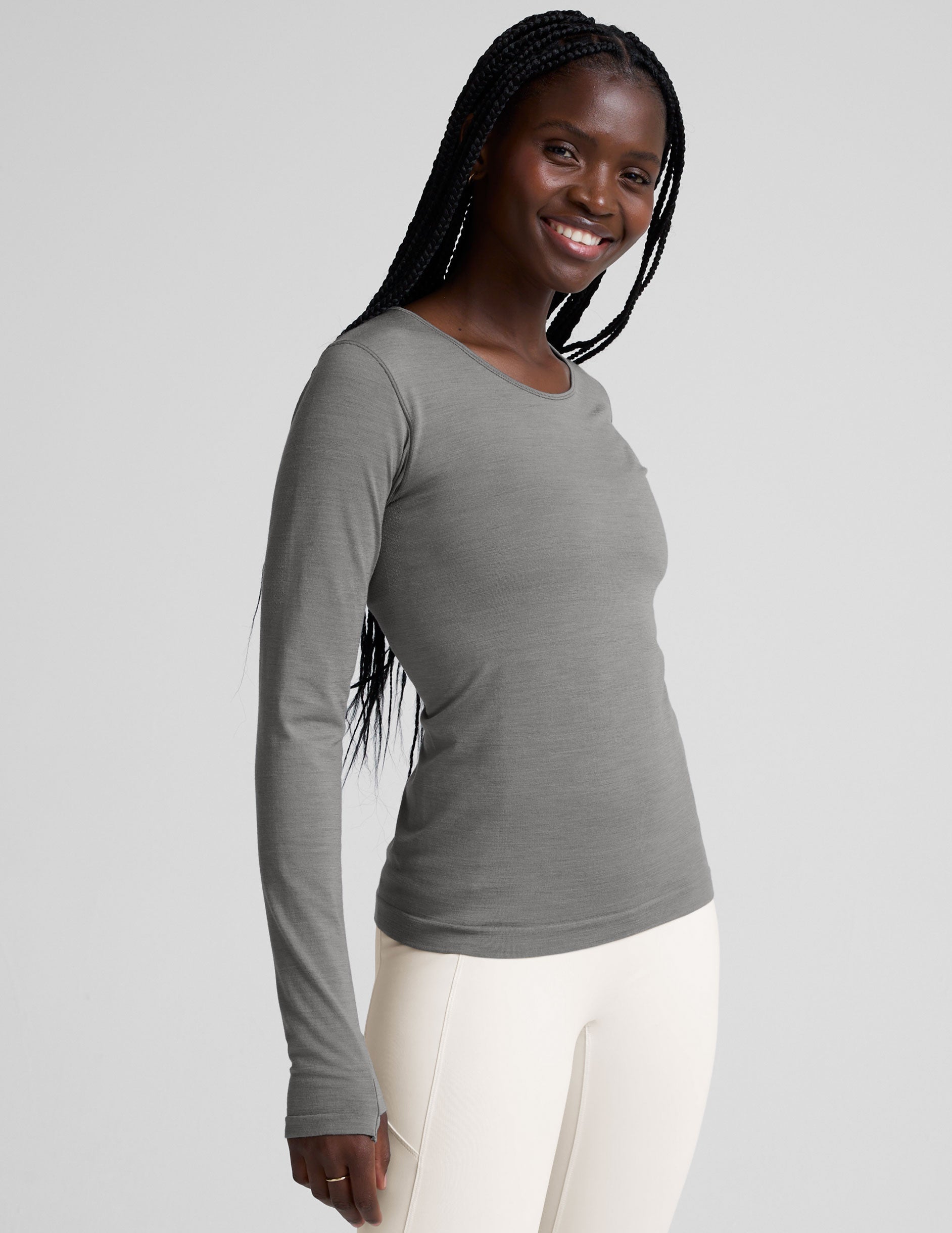 model wearing a gray long-sleeve crewneck top and white pants on a plain background.