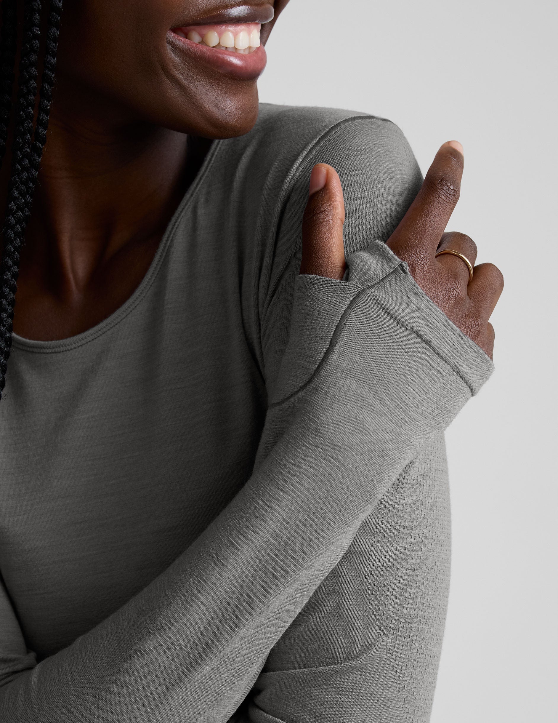 model wearing a gray long-sleeve crewneck top and white pants on a plain background.