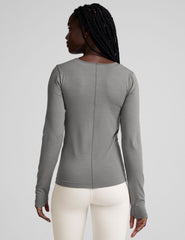 model wearing a gray long-sleeve crewneck top and white pants on a plain background.